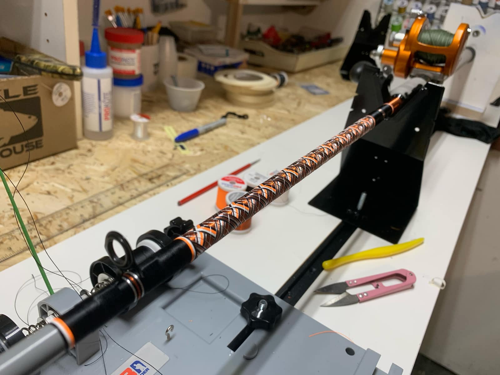 Workshop bench scene with rod-building tools, partial rod in progress, and component parts laid out