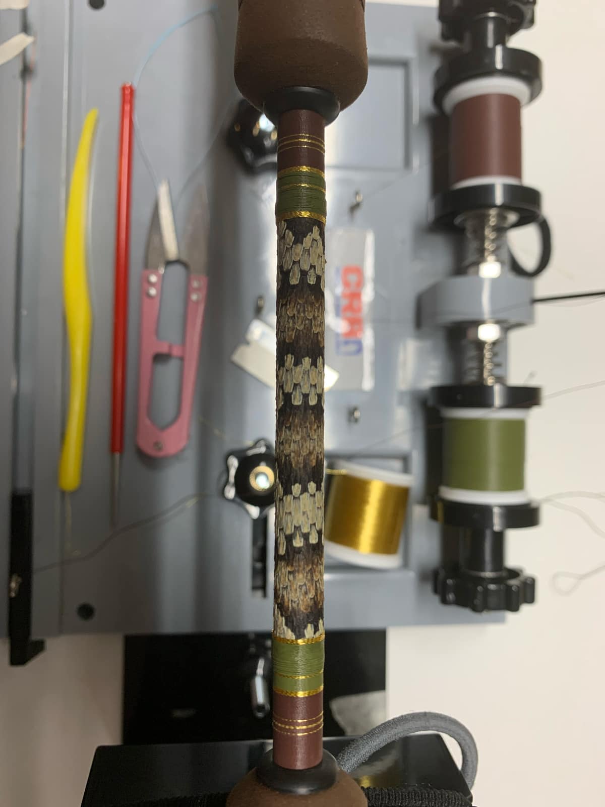 Detail of a decorative thread wrap along a rod blank, with a secondary color accent running through the primary wrap