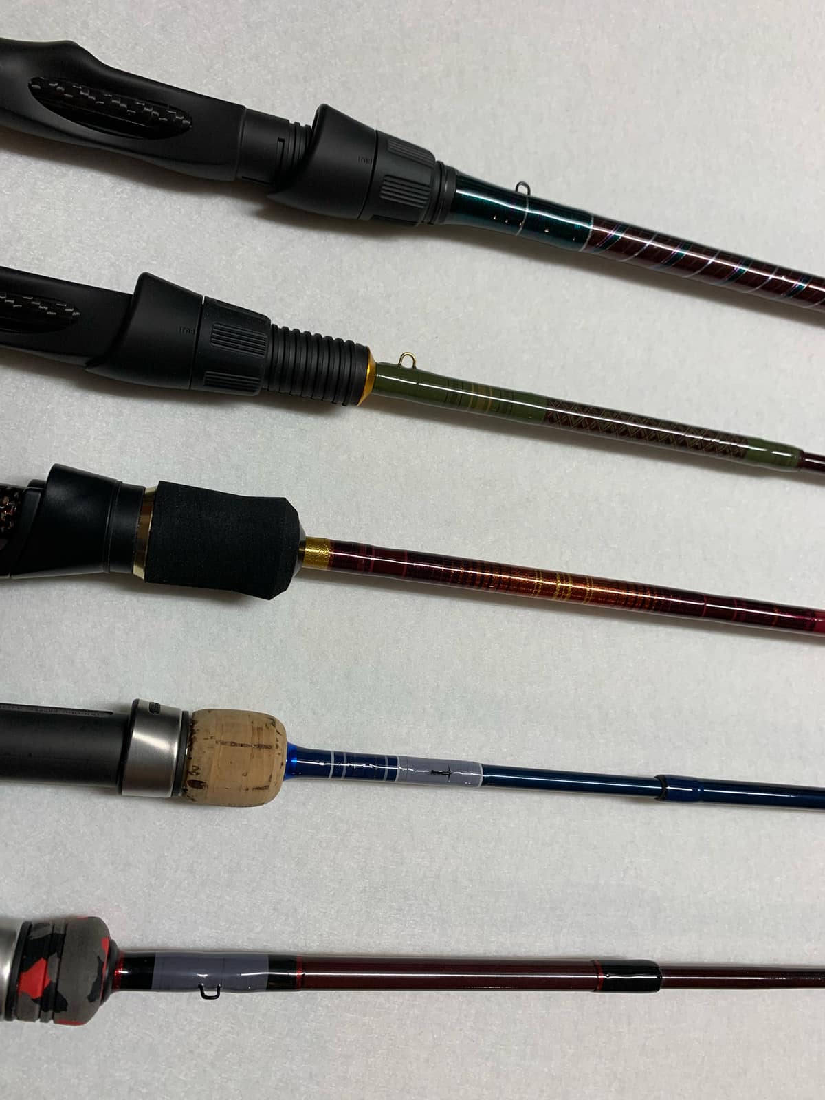 A custom rod laid flat on a neutral surface, showing the grip, reel seat, and first guides of the build