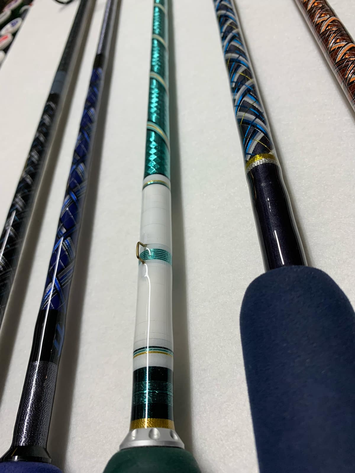 Close-up of a decorative thread wrap on a custom rod, navy and gold threads bound under epoxy